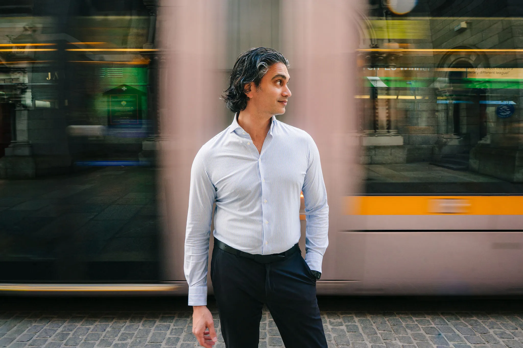 Aaron Rodericks on a Dublin street as a tram passes behind him
